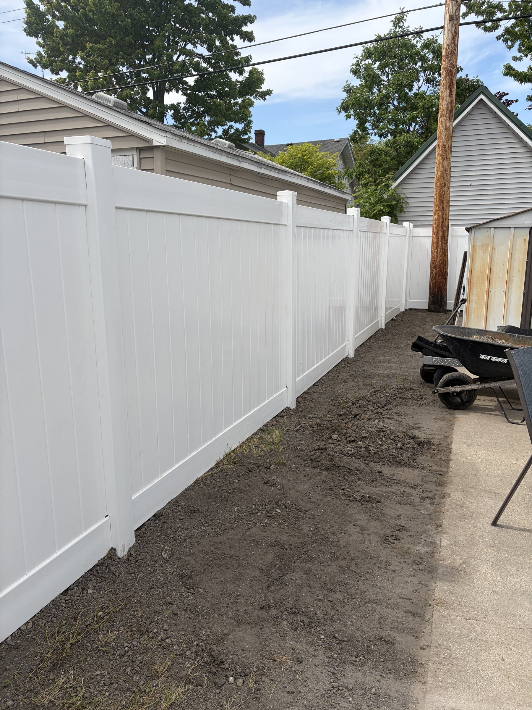 Long run of white vinyl privacy fence along a side yard next to a garage