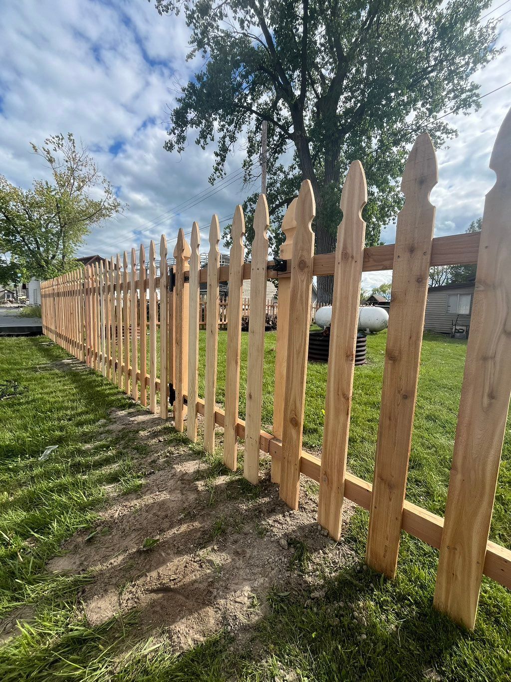 Cedar picket fence with pointed French Gothic pickets along a yard