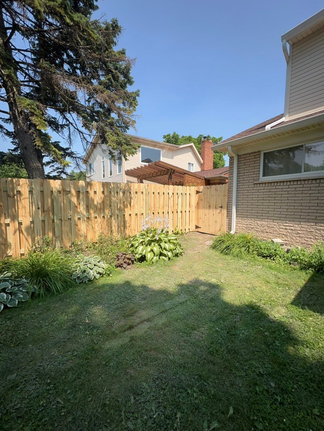 Wood shadow box fence closing off a side yard next to a brick home